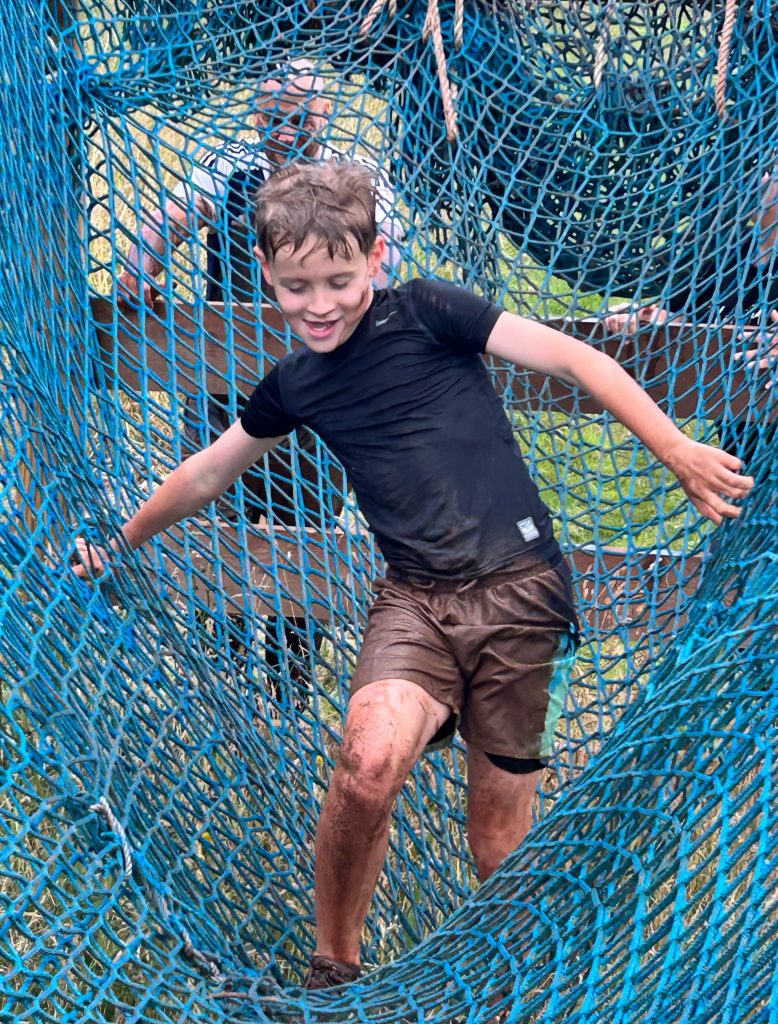 Child climbing net obstacle on the Wild Cairns assault course