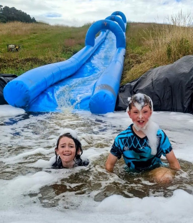 Two children in the foam at the bottom of a water slide at Wild Cairns